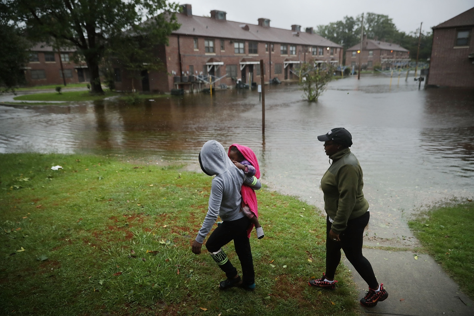 Three people survey the flooding at the Trent Court public housing project in New Bern, North Carolina after Hurricane Florence. A federal program to build new affordable apartments in the city took more than five years to complete.