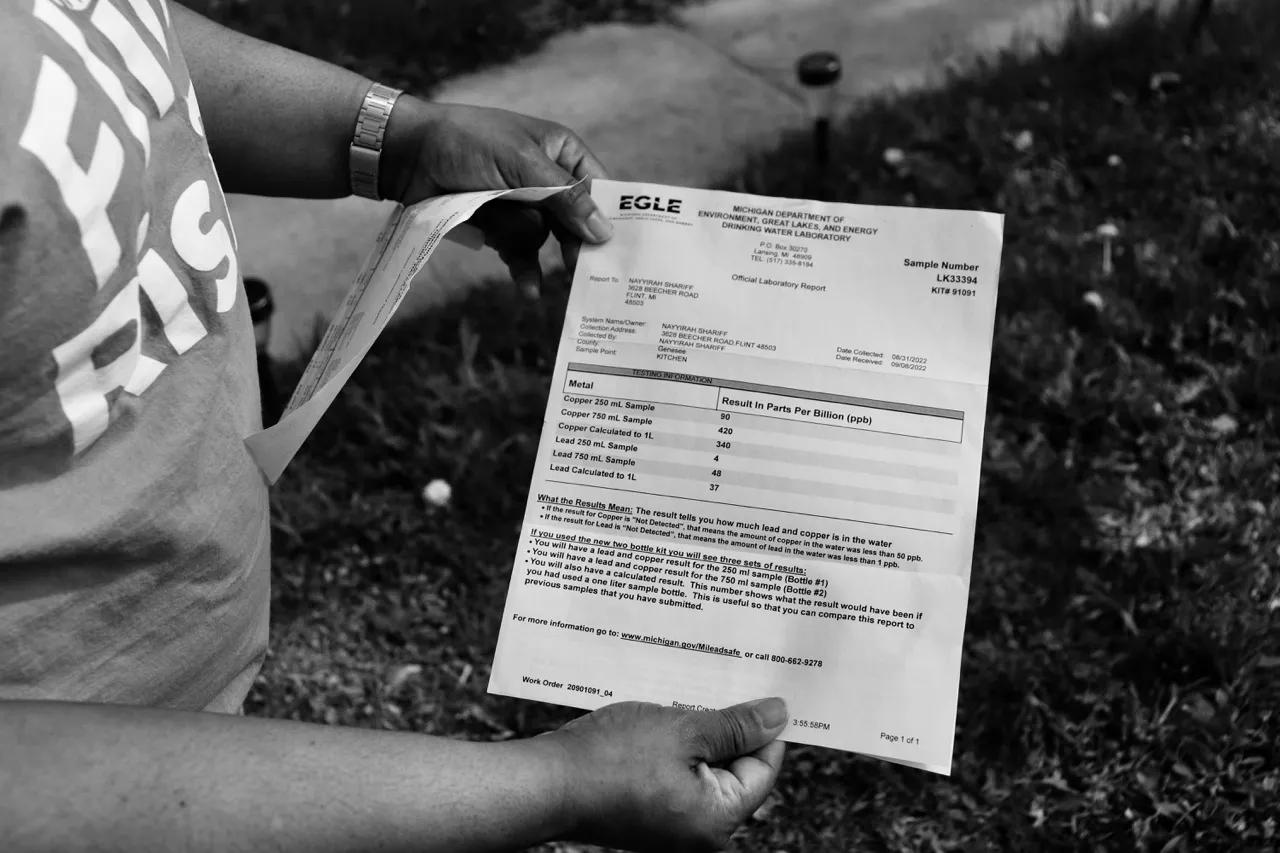 A woman holds a piece of paper with test results on it.