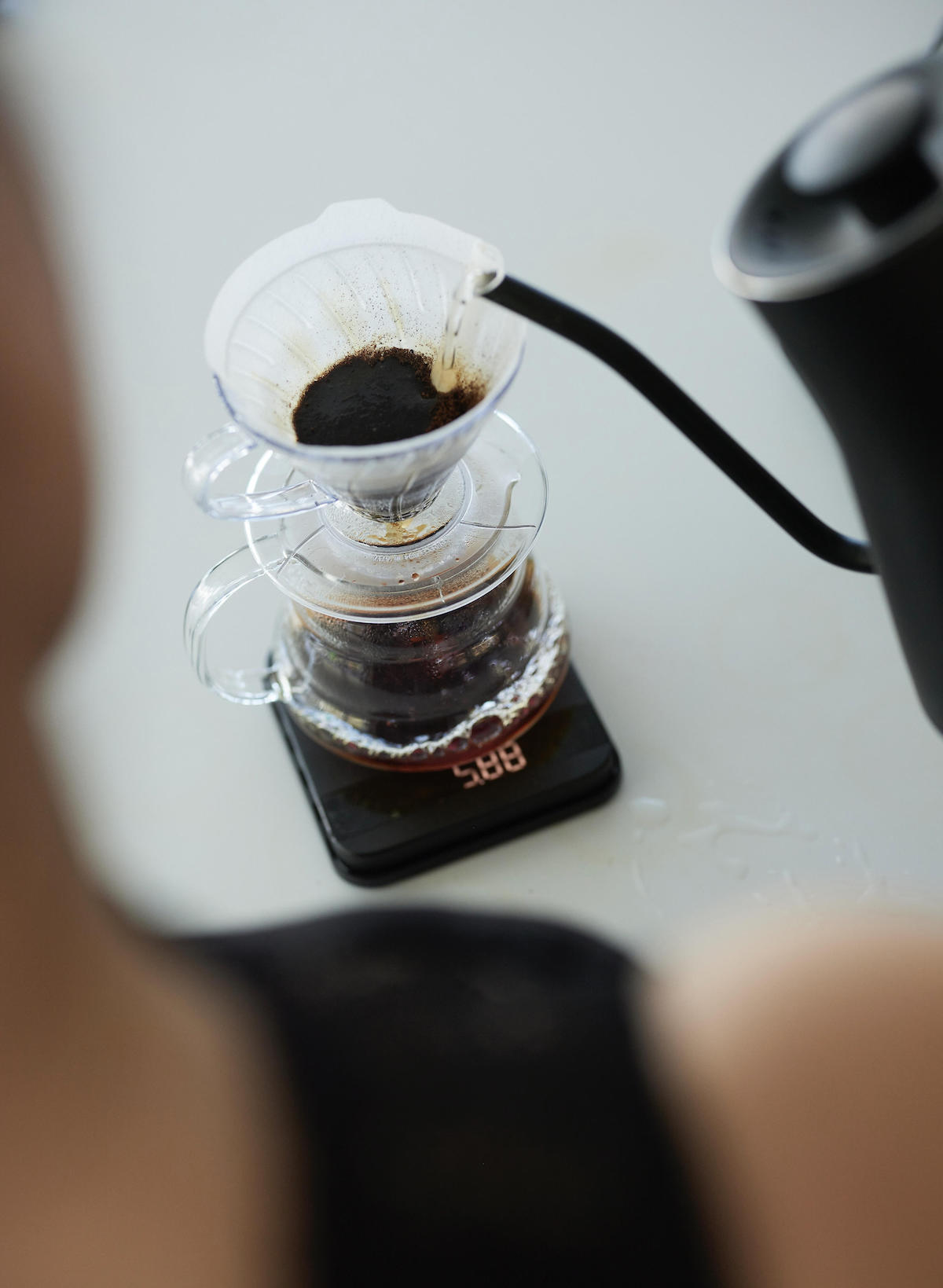 A pesron pours coffee into filter on scale