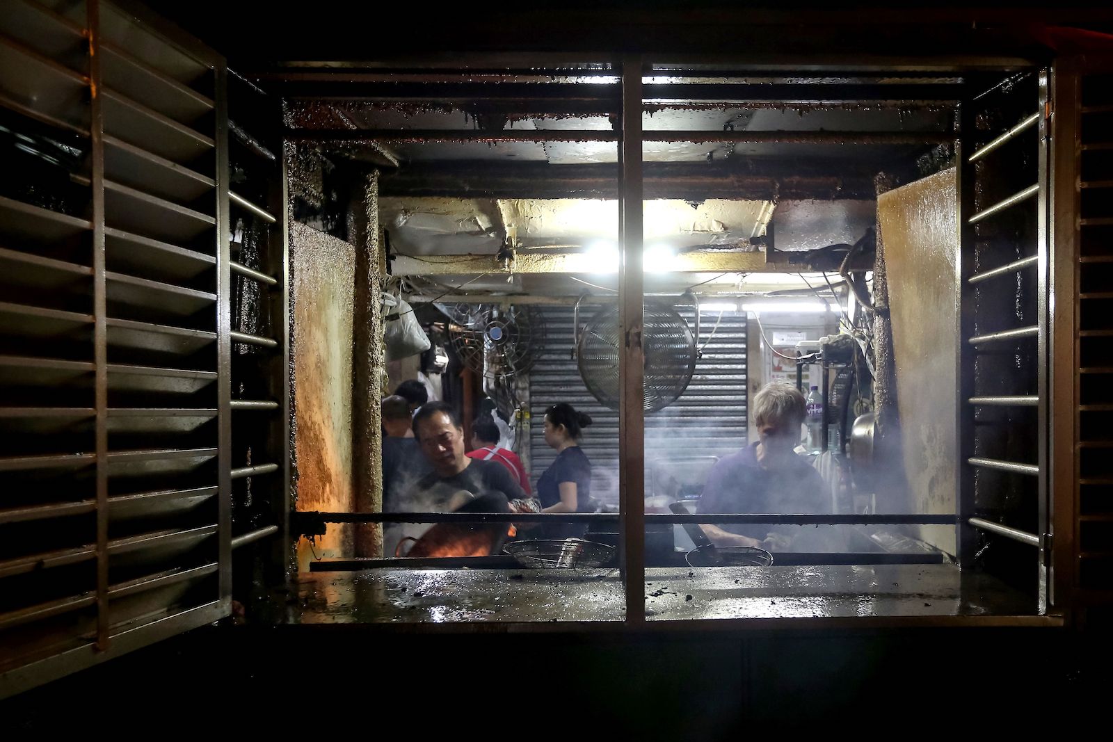 a person cooks over a hot stove in an open-air restaurant