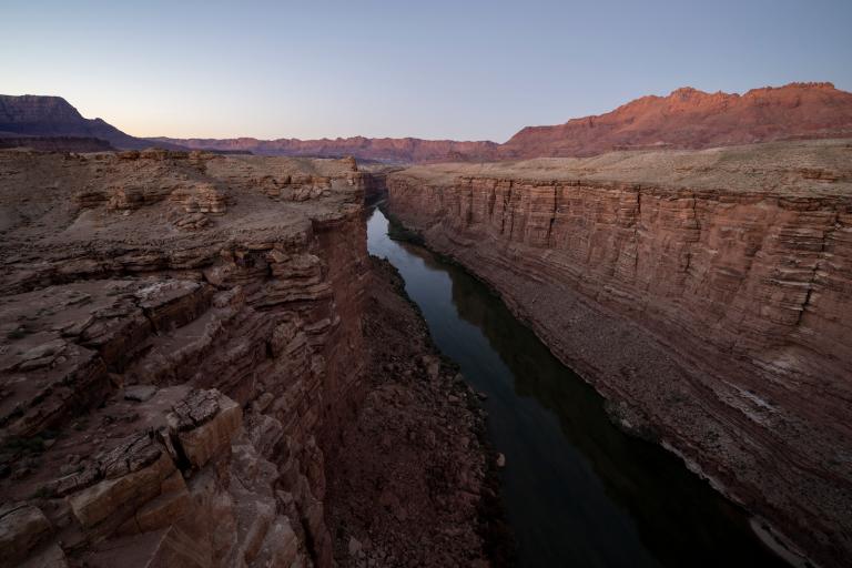 a stream runs through a large red rock canyon at dusk
