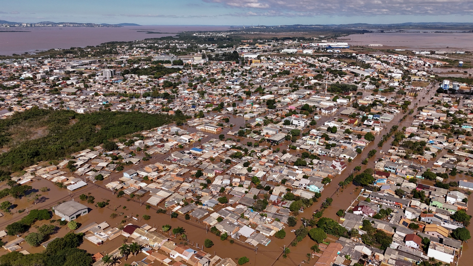 An aerial view of thousands of city homes stranded in brown flood water.