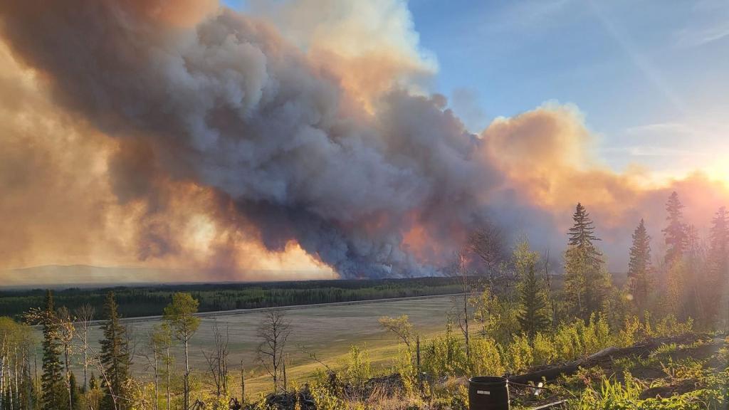 thick spiral of smoke drifts over field obscuring blue sky and sun
