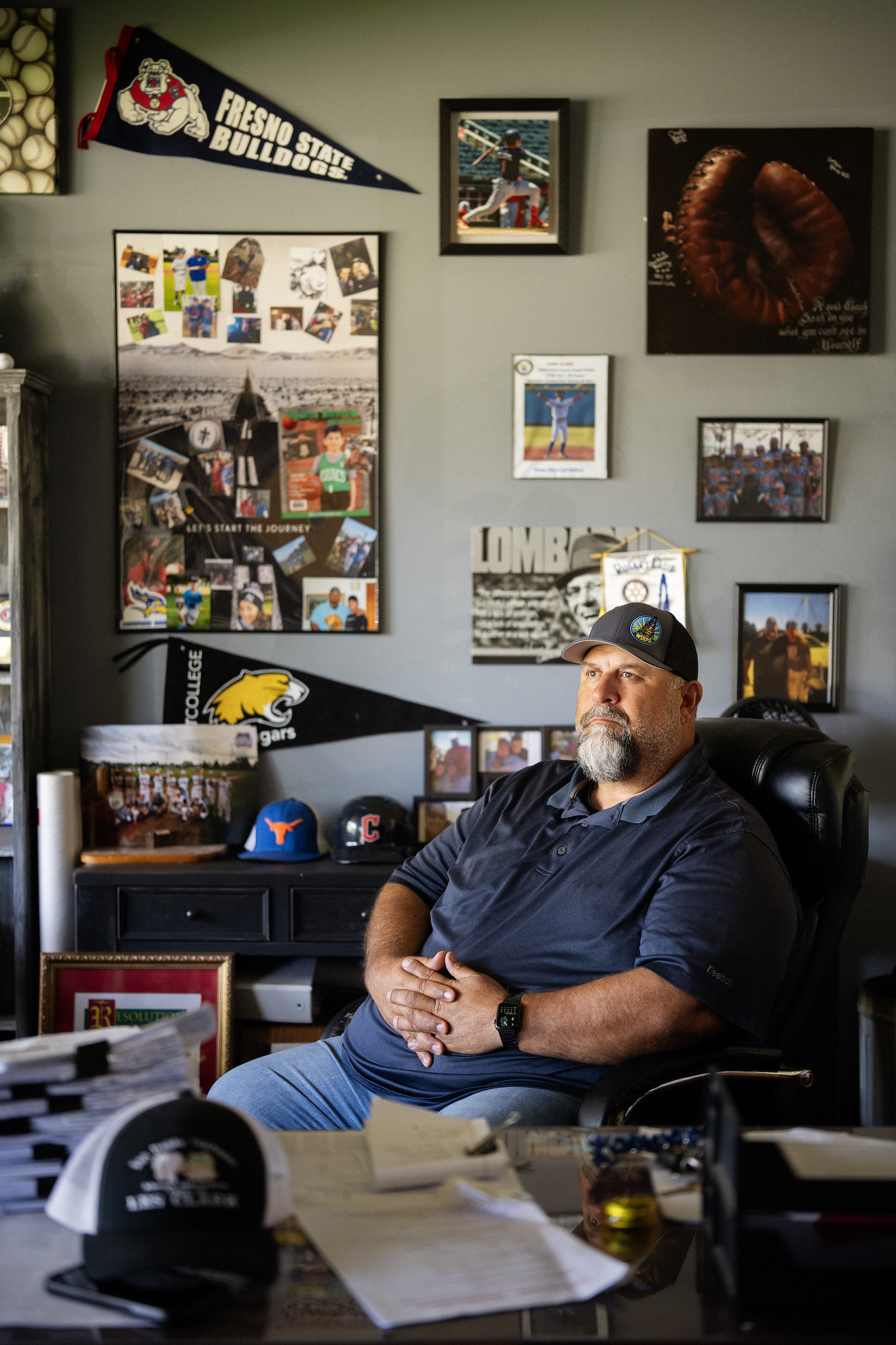 A man sits in an office decorated with many pictures