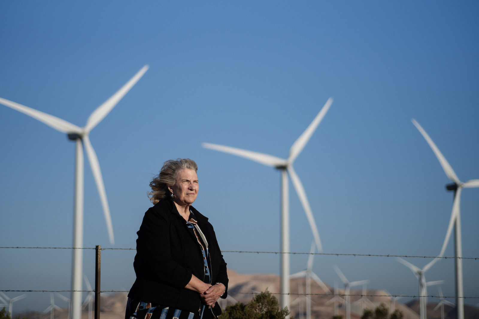 A woman stands near wind turbines