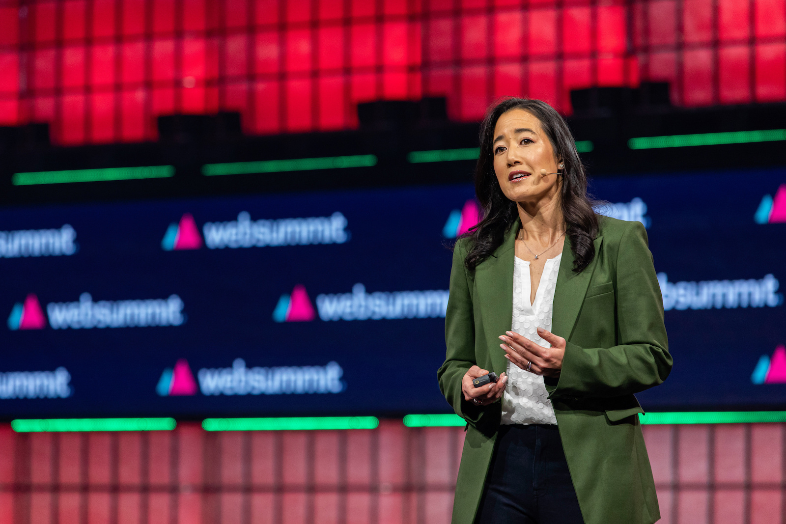 A woma in a blazer talks in front of a large screen with web summit logos