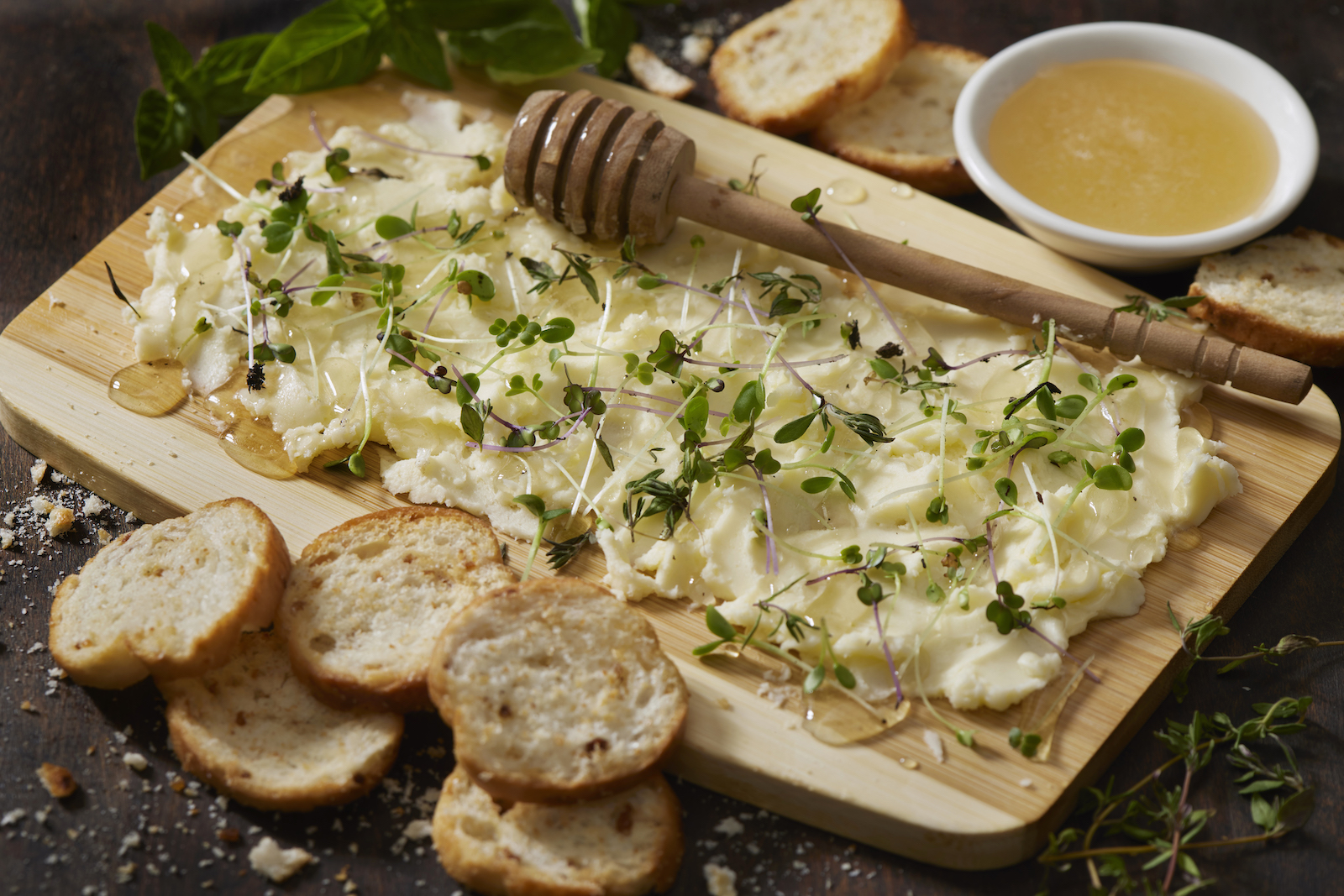 A wooden board covered with pats of butter and herbs