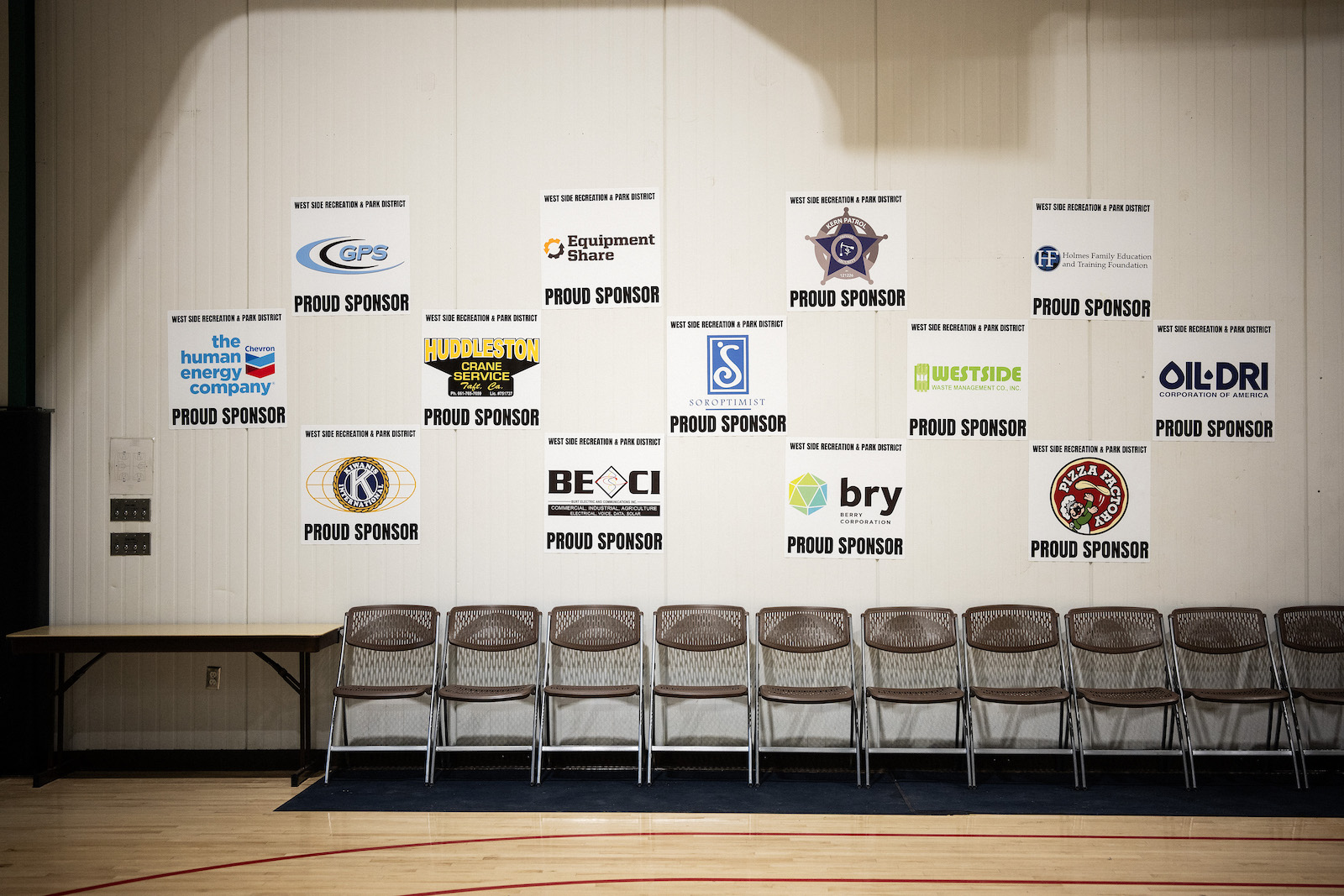 A row of chairs in front of a wall with many oil and gas company logos on it