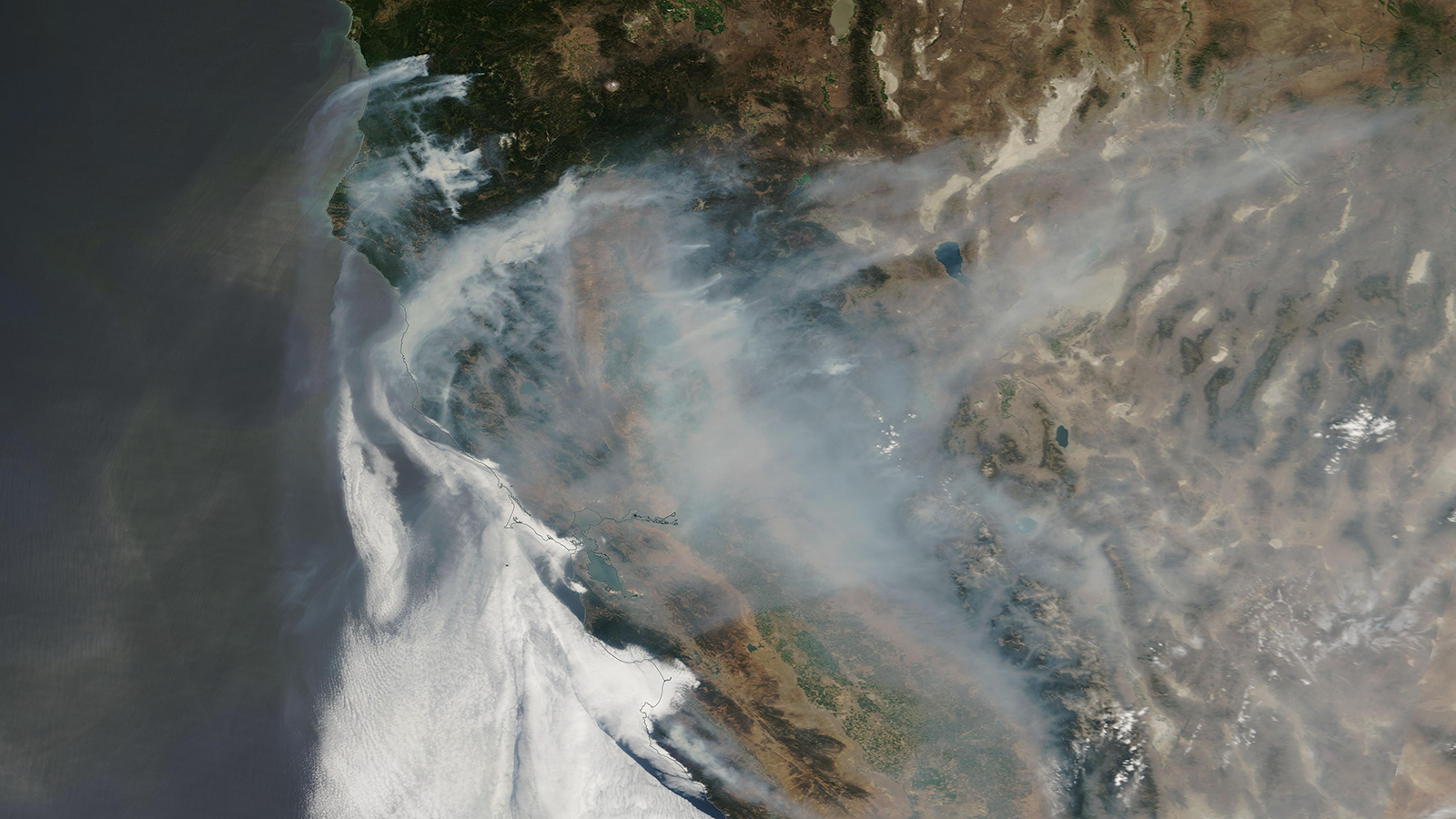 An aerial view of wildfire smoke across a brown satellite view of earth