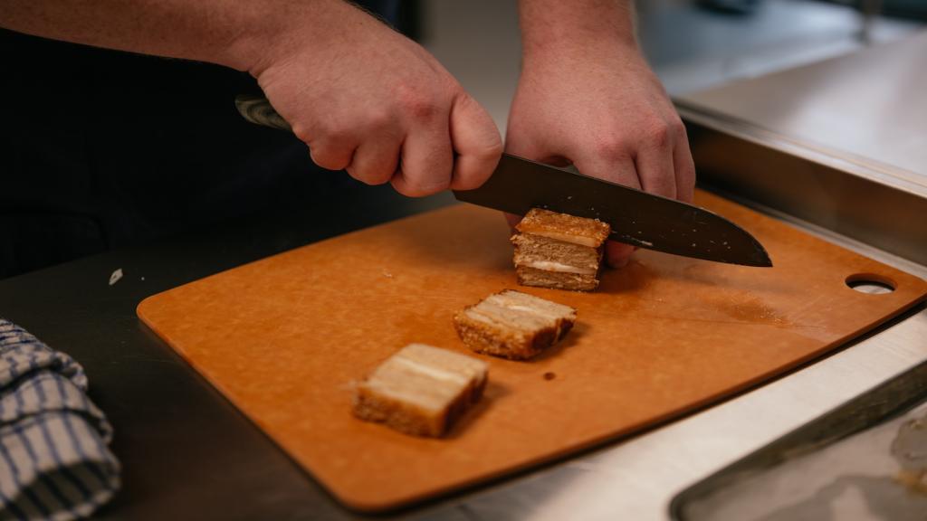 A chef chops a plant-based pork belly.