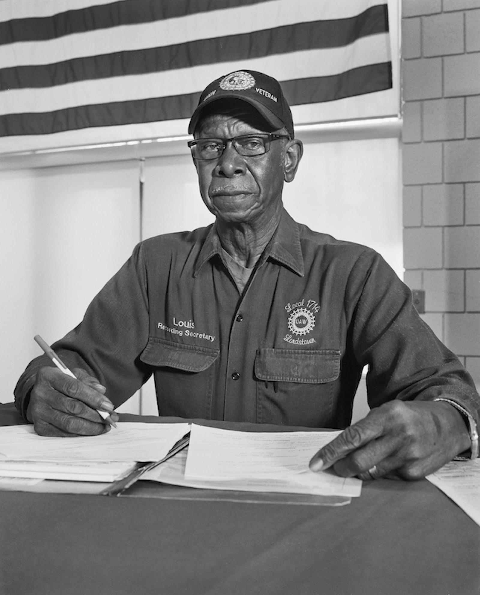 A black and white photo of a man in a uniform sitting at a desk with paperwork