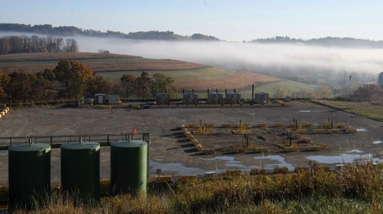 A misty field with an industrial installation on the edge.