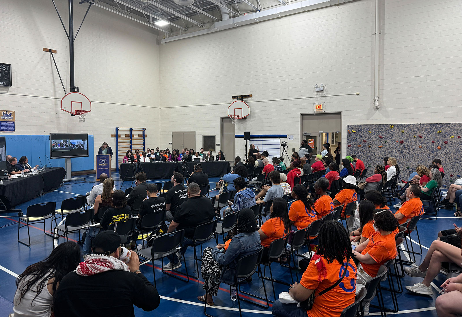 People sitting in school gymnasium listen to Chicago Teachers Union contract negotiations
