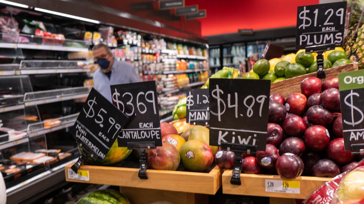 A photo of a grocery store produce aisle with signs showing prices on black and white cards