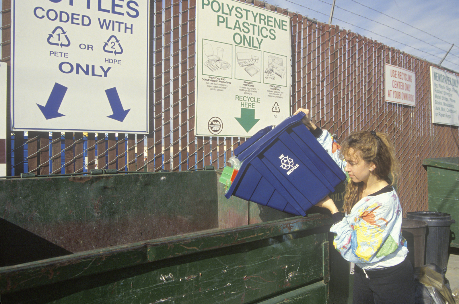 A woman recycling plastics in separate recycling containers at the Santa Monica Recycling Center, California.