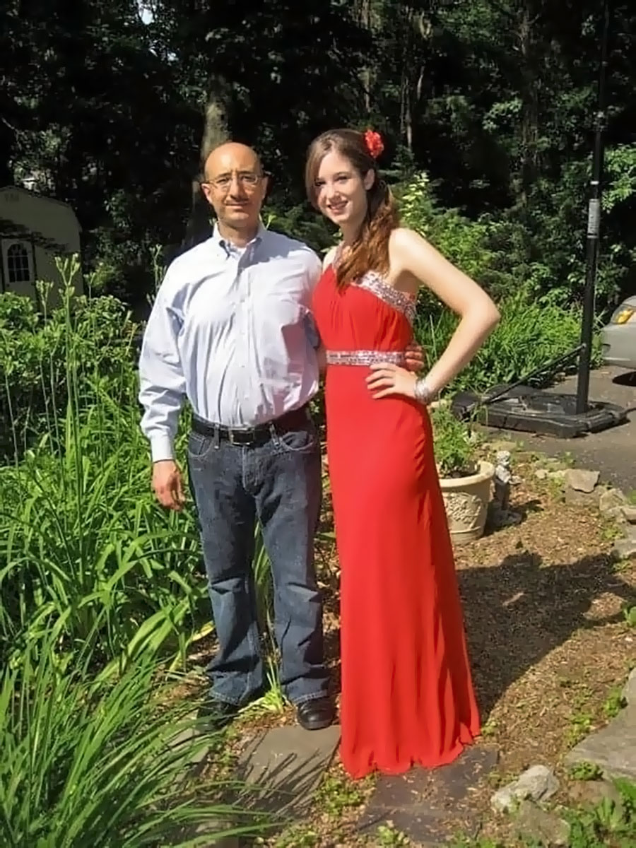 A girl in a red prom dress standing next to her father