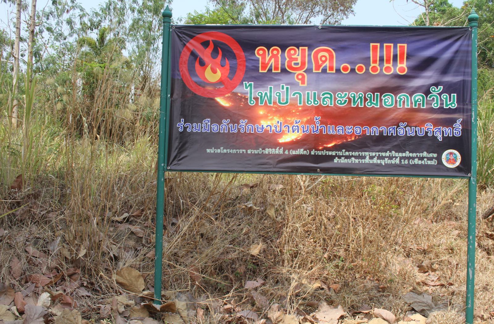 A banner on the side of the road shows a fire symbol with a line through it, with writing in Thai
