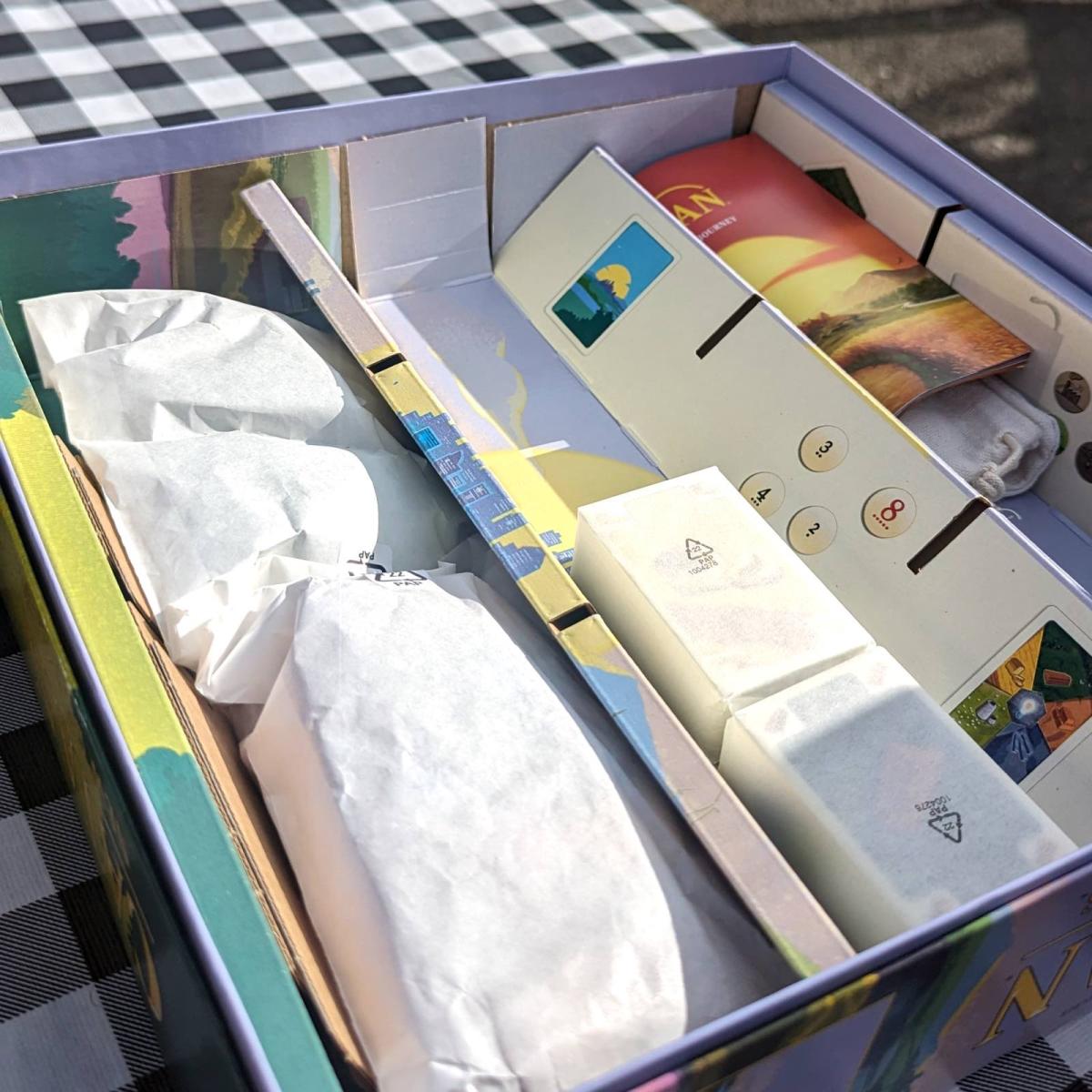 The inside of a board game box, showing card decks and other items wrapped in paper
