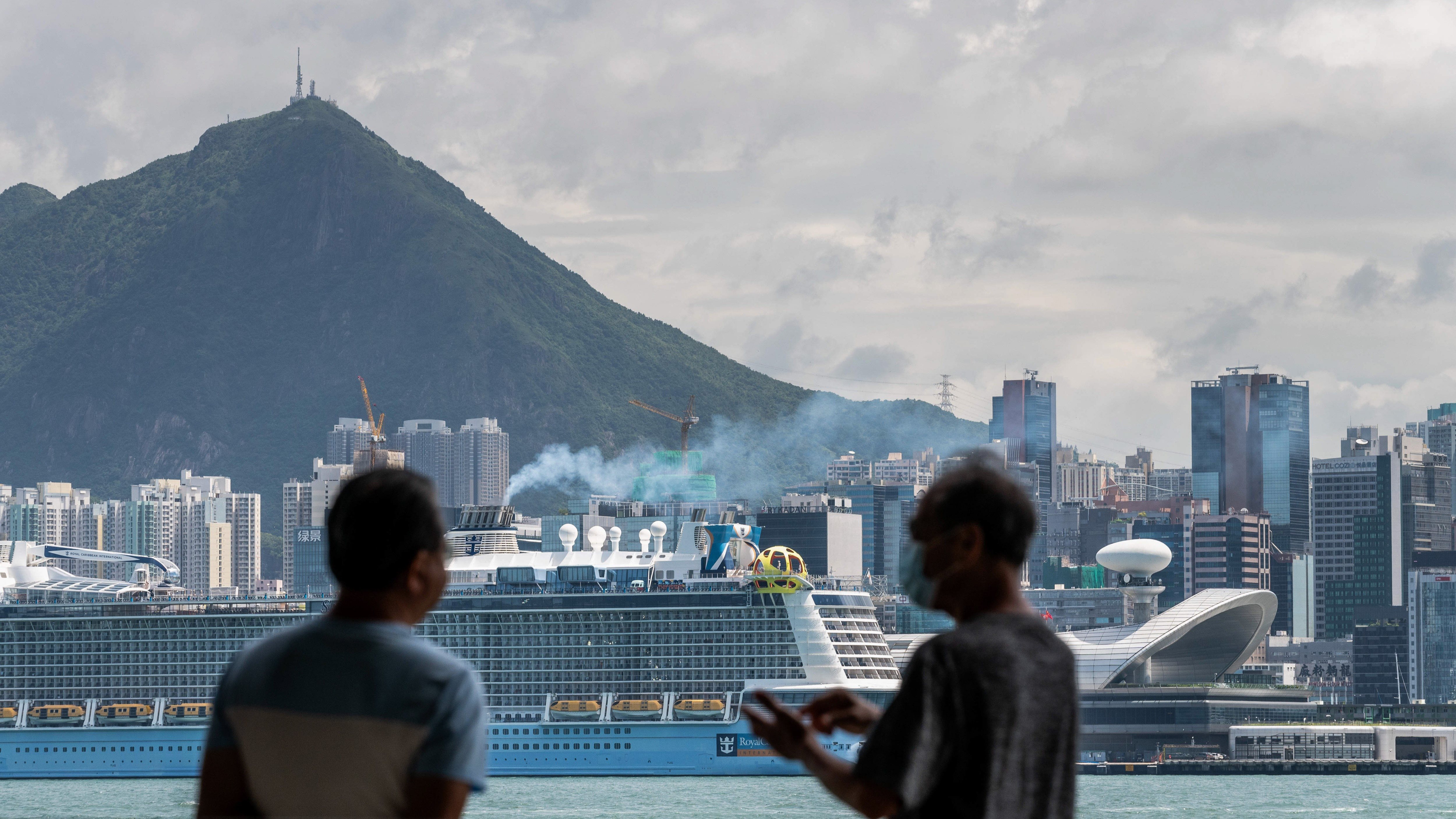 Two men have a conversation as Royal Caribbean International's Spectrum of the Seas docked across the harbour at the Kai Tak Cruise Terminal in Hong Kong.