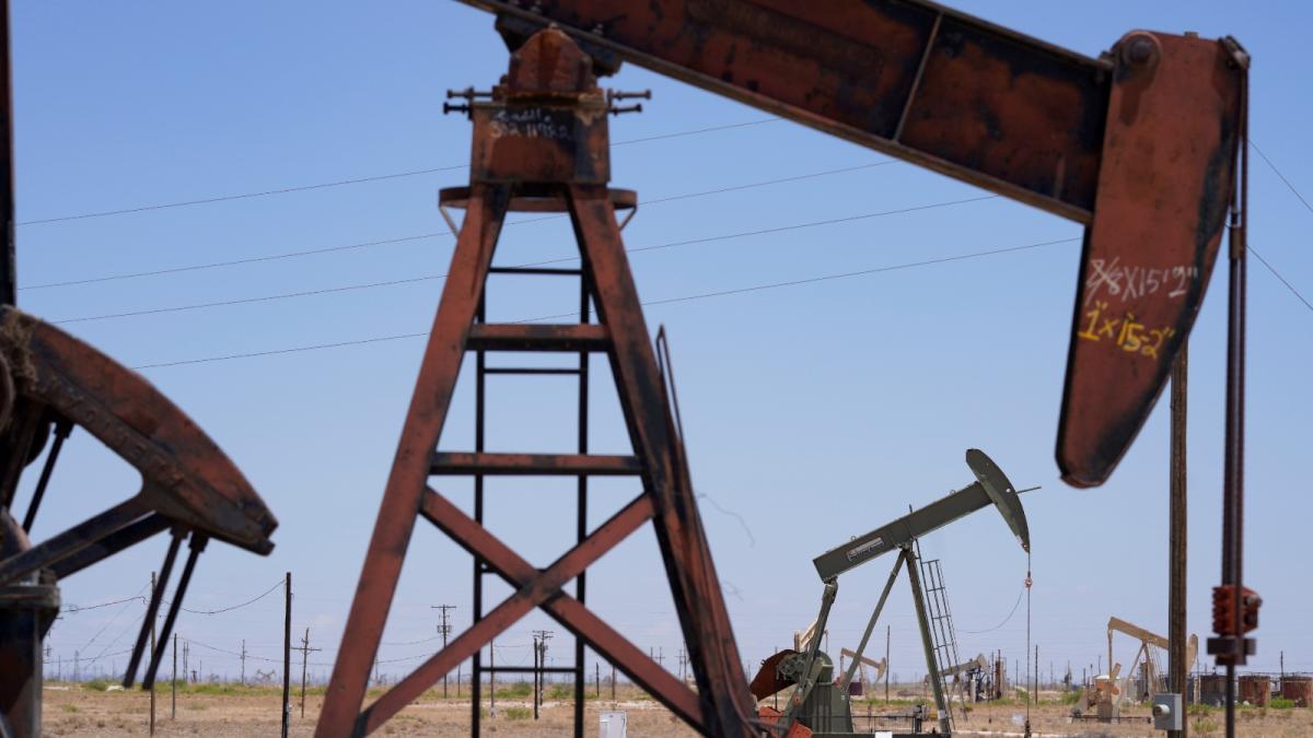 Several red oil derricks sit in a barren field.