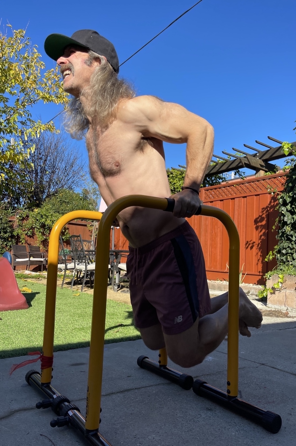 A man does bar dips on an outdoor play structure