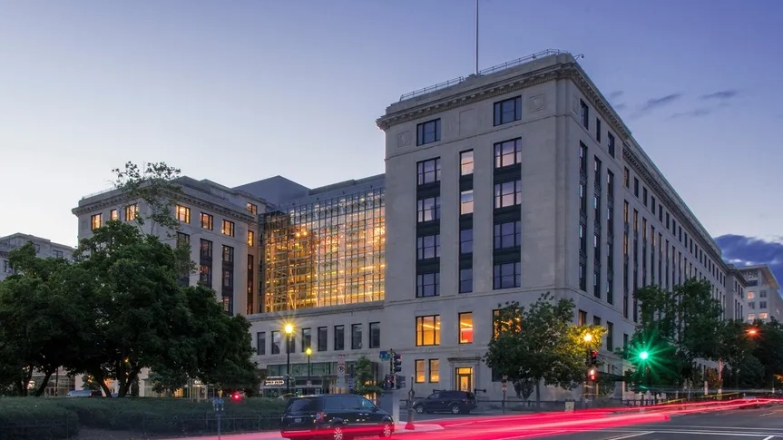 At dusk, a large white building stands illuminated.