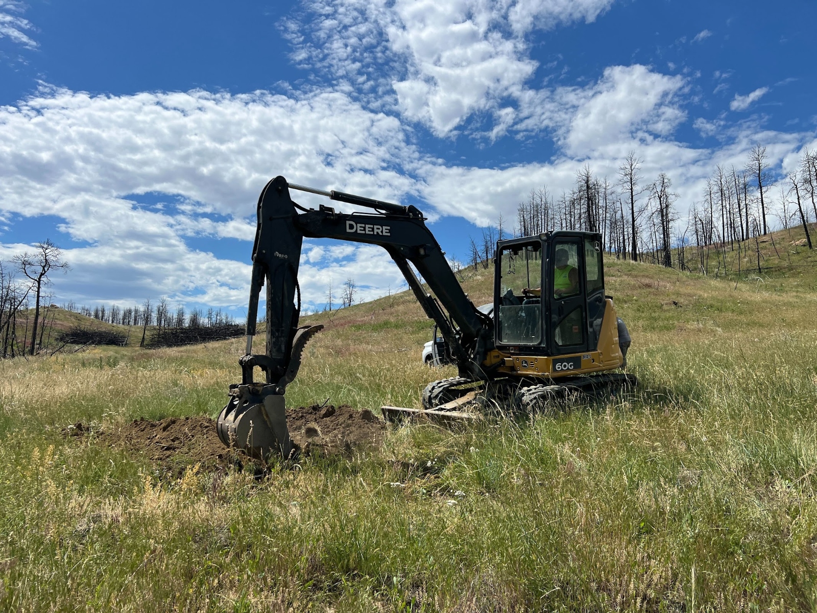Heavy machinery prepares soil for a wood vaulting project in a grassy field