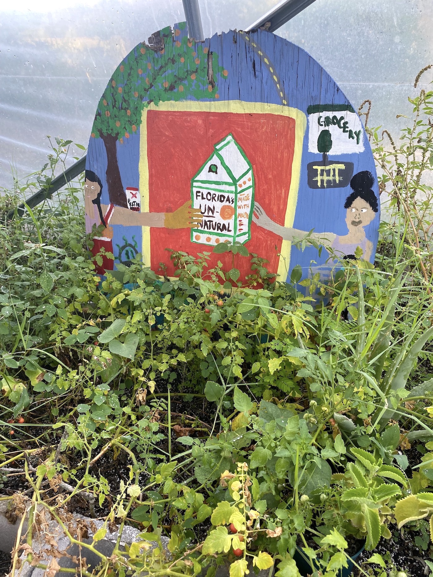 A sign with a painted milk carton on it and plants growing