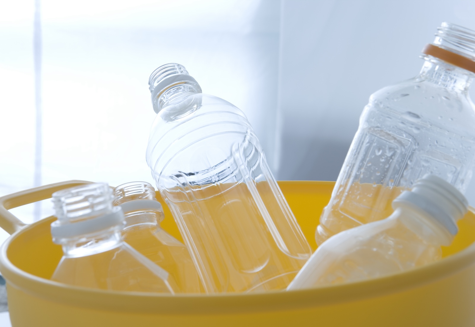 Empty plastic water bottles in a yellow bucket.