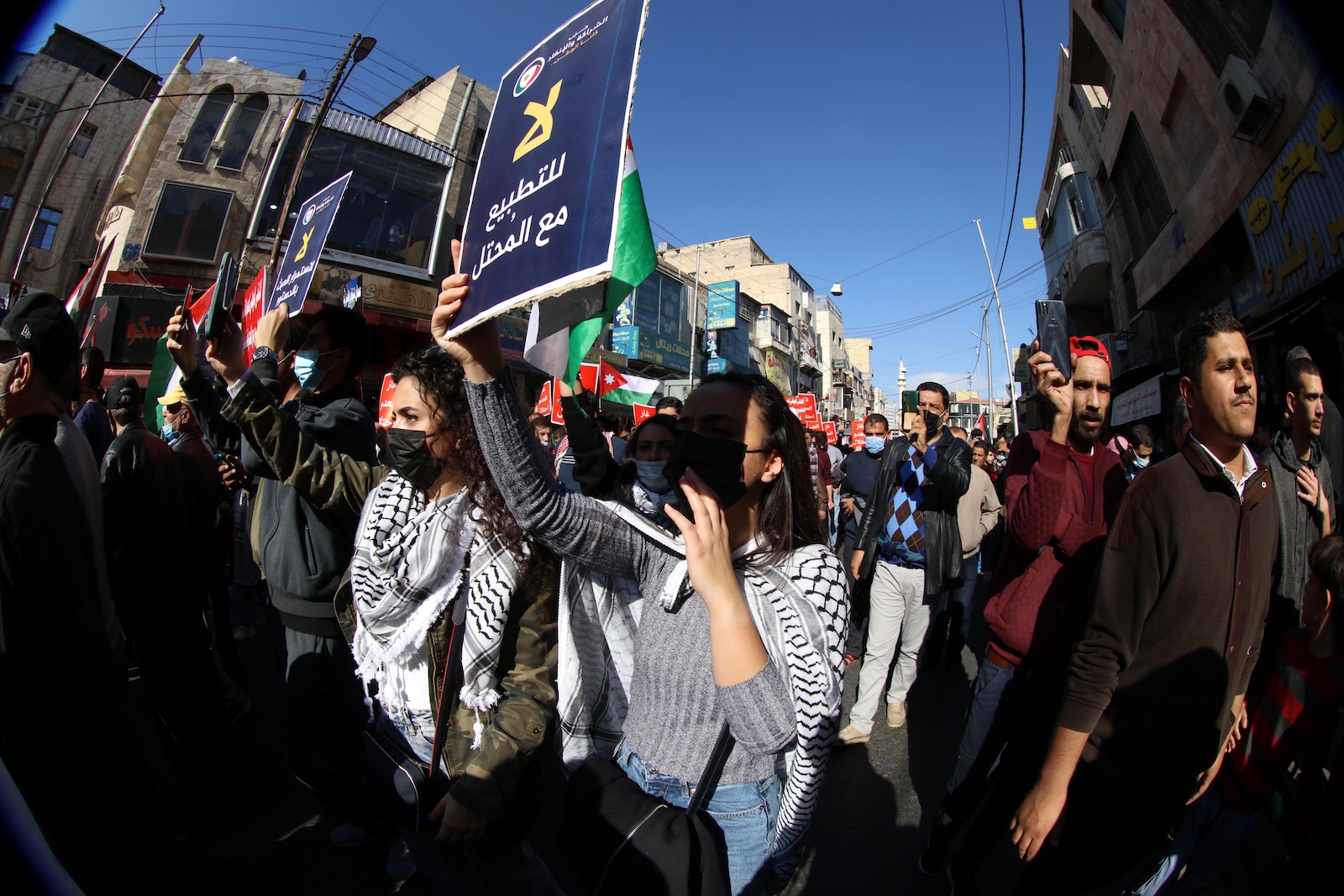 A group of people wave signs in arabic while march in the streets