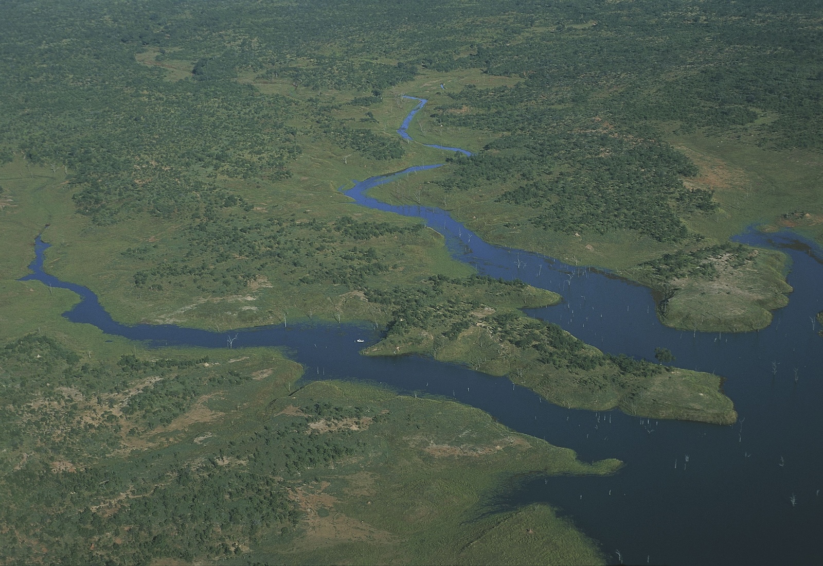 Aerial view of part of Lake Kariba in Zimbabwe. To the left of the lake the land is green from tree cover.