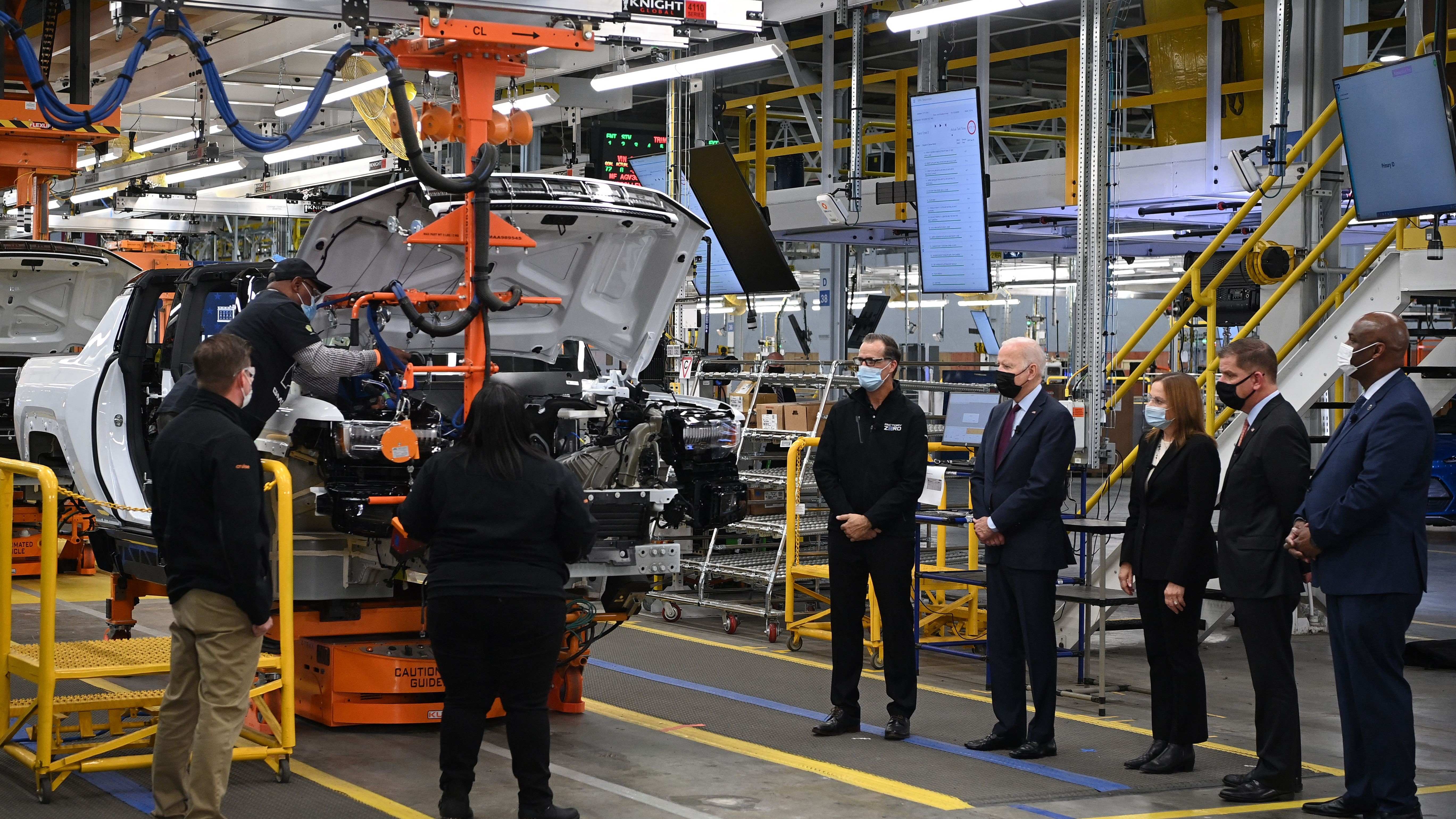 President Joe Biden and others stand on the floor of an EV assembly plant.