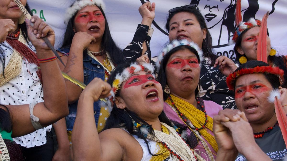 A group of women with headdresses and red face paint shout together