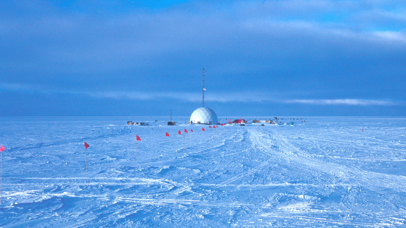 a snowy expanse, red flags leading to a domed science station