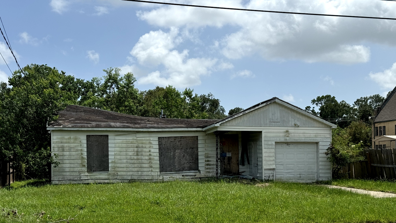 A dirty abandoned home near a green lawn