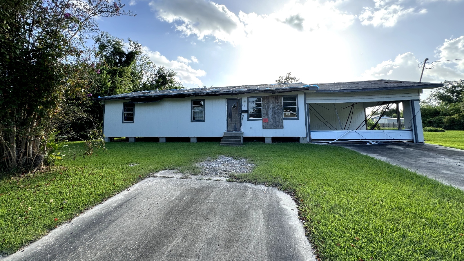 A blue abandoned home near a green lawn