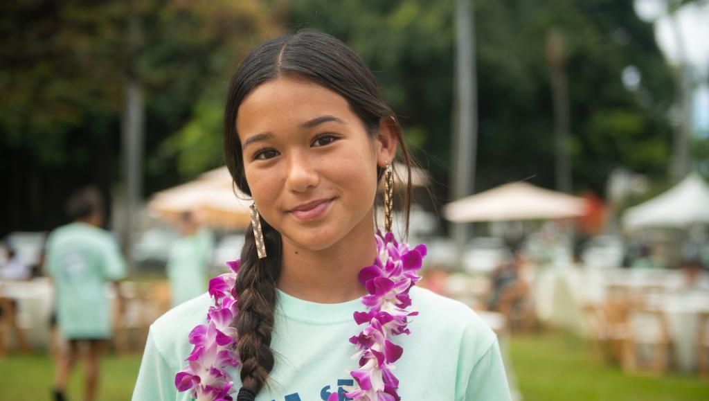 Kaliko smiles wearing a lei on a sunny day outside Iolani Palace in Honolulu.