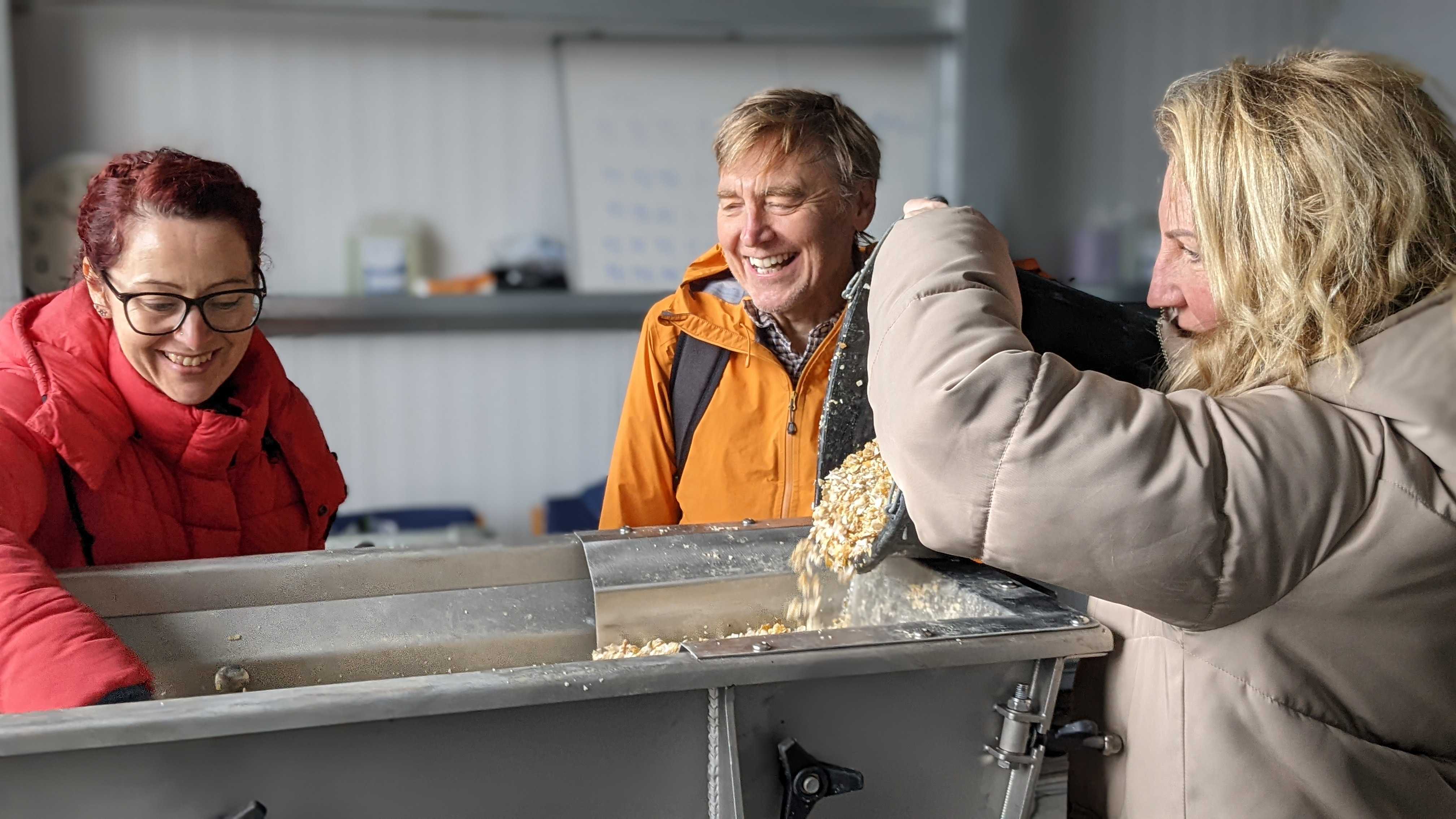 A group of people laughing while throwing shells into a container.