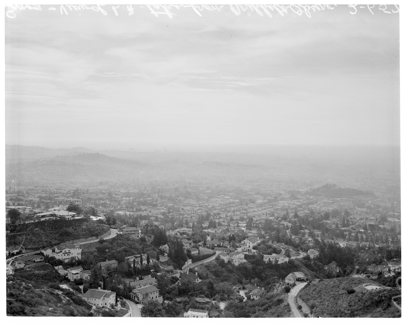 A black and white photo of smog over a dense cityscape