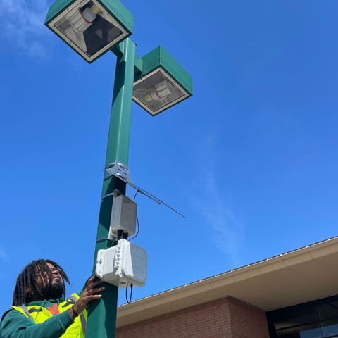 Man affixes air quality monitor to lamp post