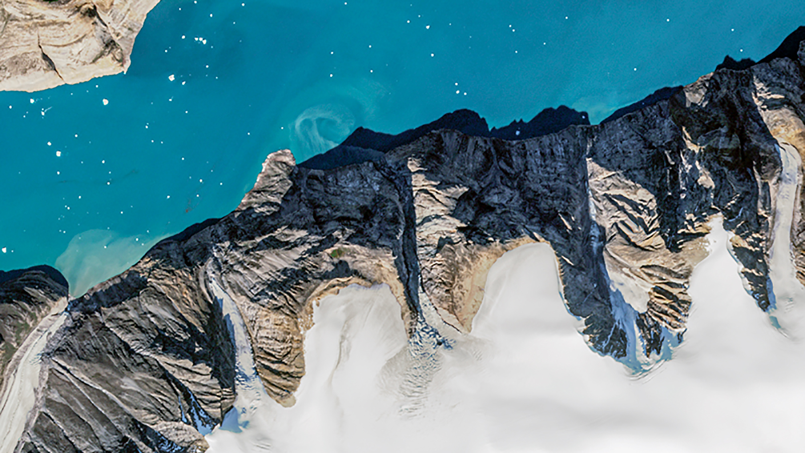 A satellite image of a fjord showing a rocky shoreline capped with ice against a turquoise blue channel of water