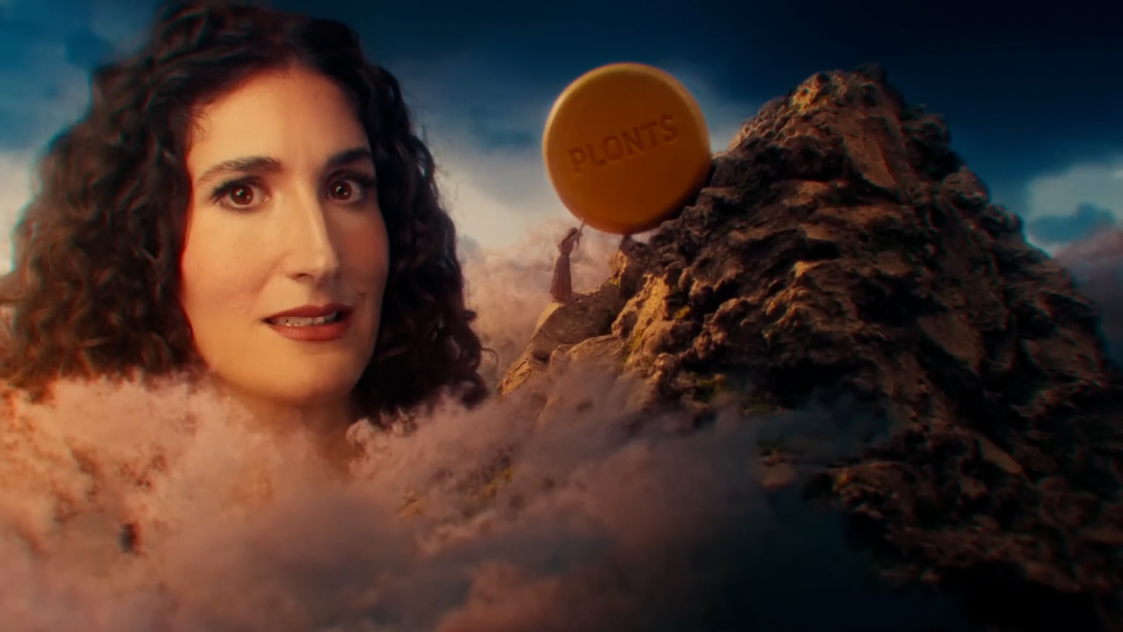 A screenshot of Plonts' launch ad, where a woman pushes a large yellow wheel of cheese with the word PLONTS written on it up a mountain, and comedian Kate Berlant's face appears in the background