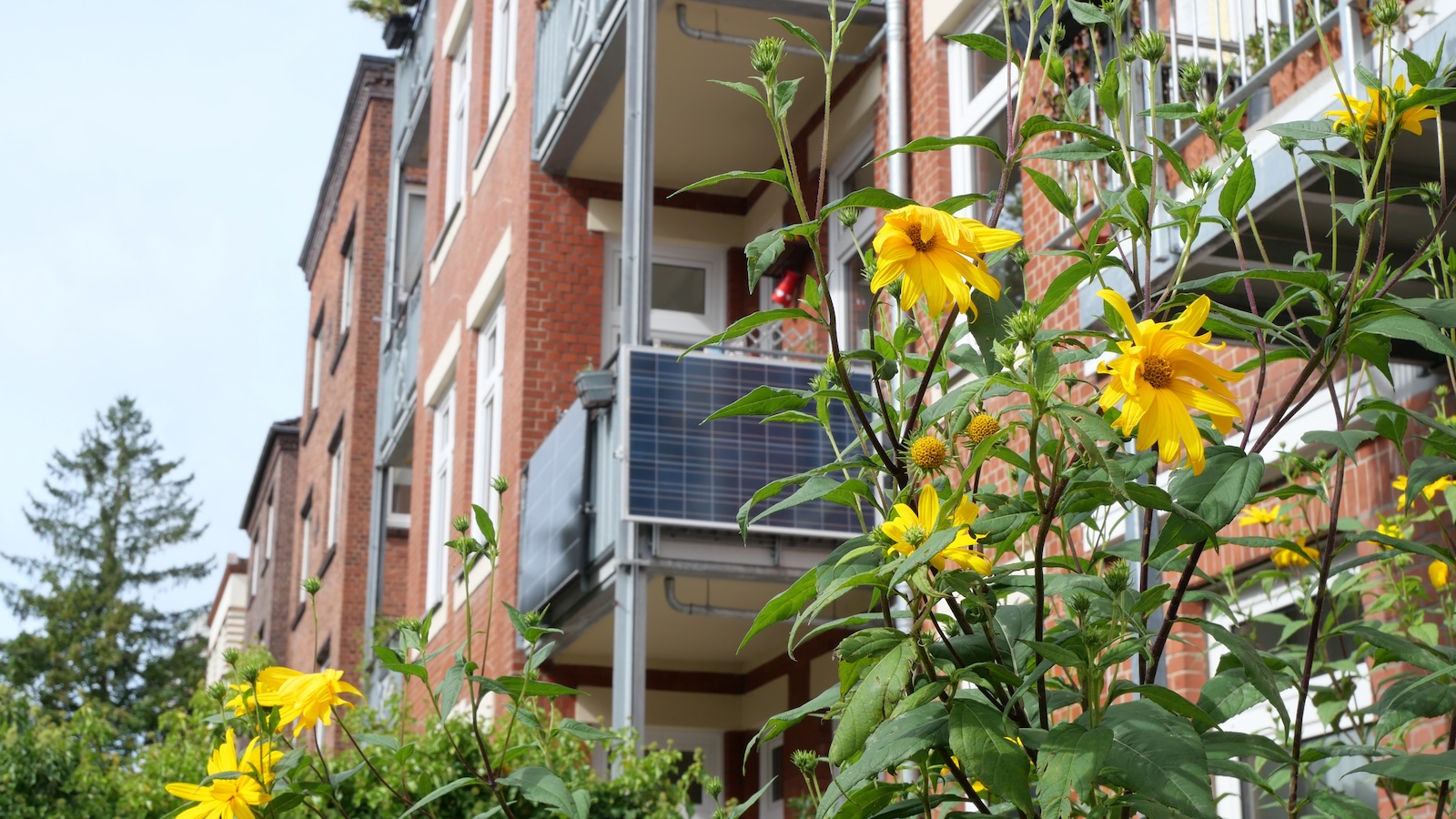 Solar panels hanging on the small balcony of a brick apartment building in Germany.