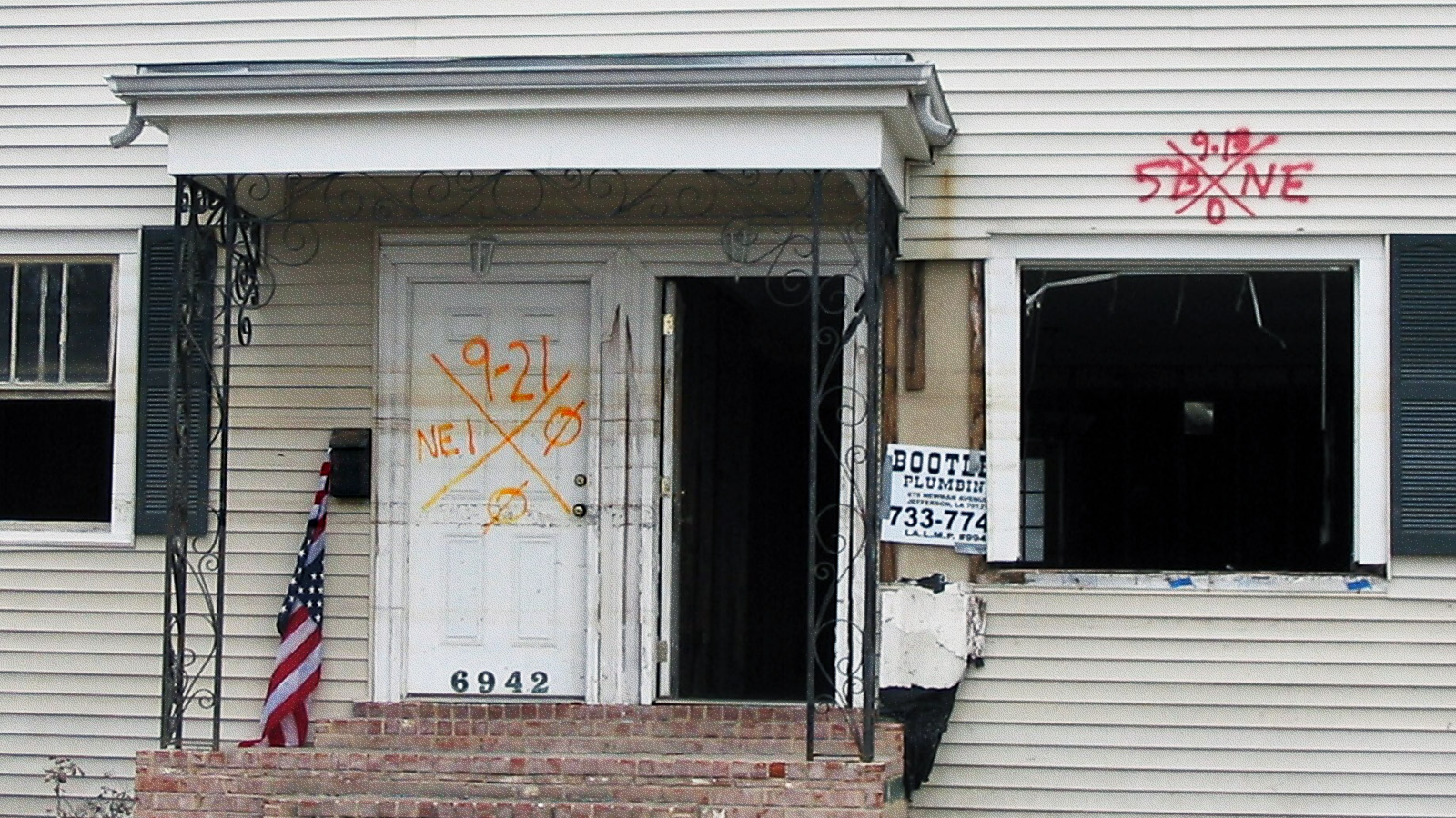 A close-up of the front of an abandoned boarded-up house