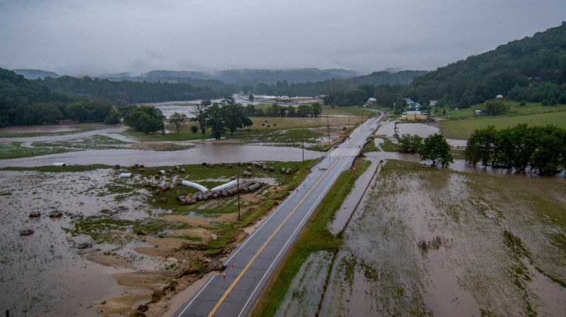 A highway cuts through a flooded area heavy with clouds.