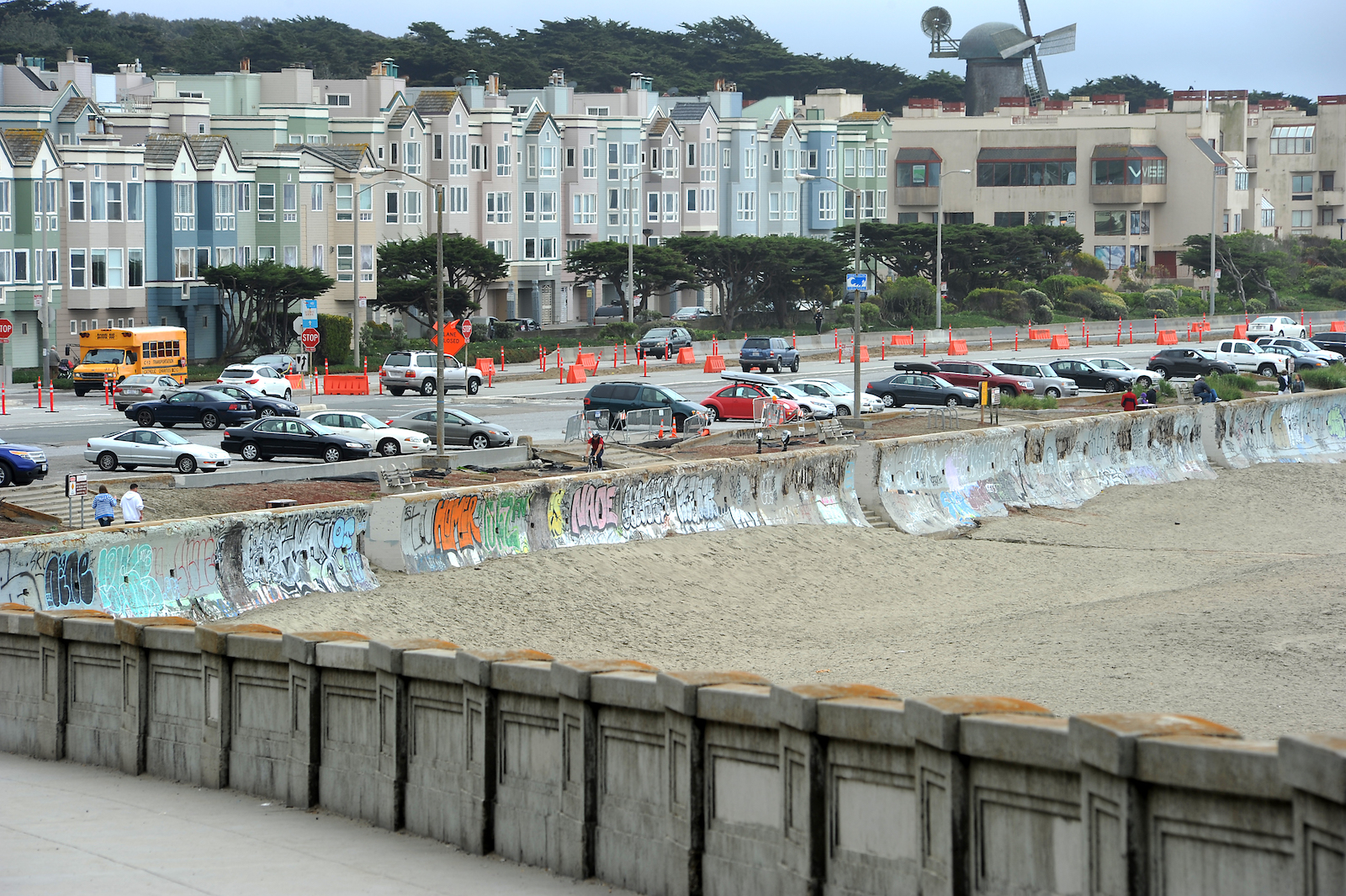 Cars in a parking lot near a line of houses and a sea wall