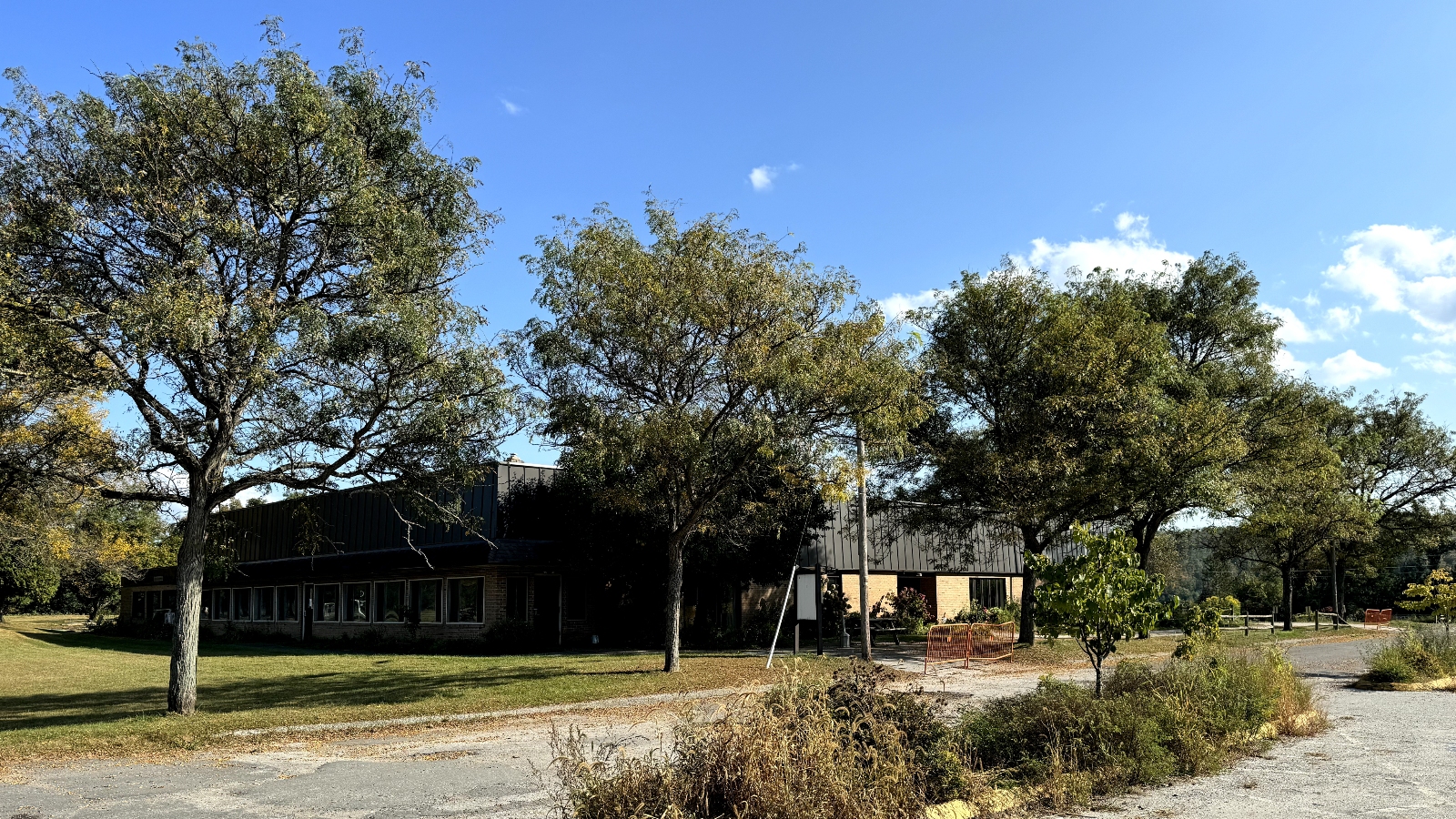 An abandoned concrete building with a parking lot in front of it.