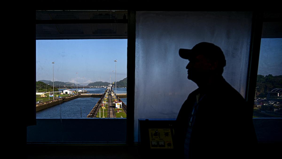 Darkened silhouette of an unidentified man in a cap looking out a window at the Panama Canal