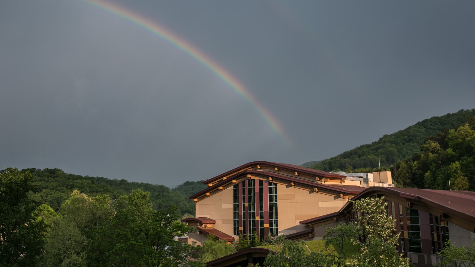 Rainbow in the dark gray sky over the tribal casino building in the mountains