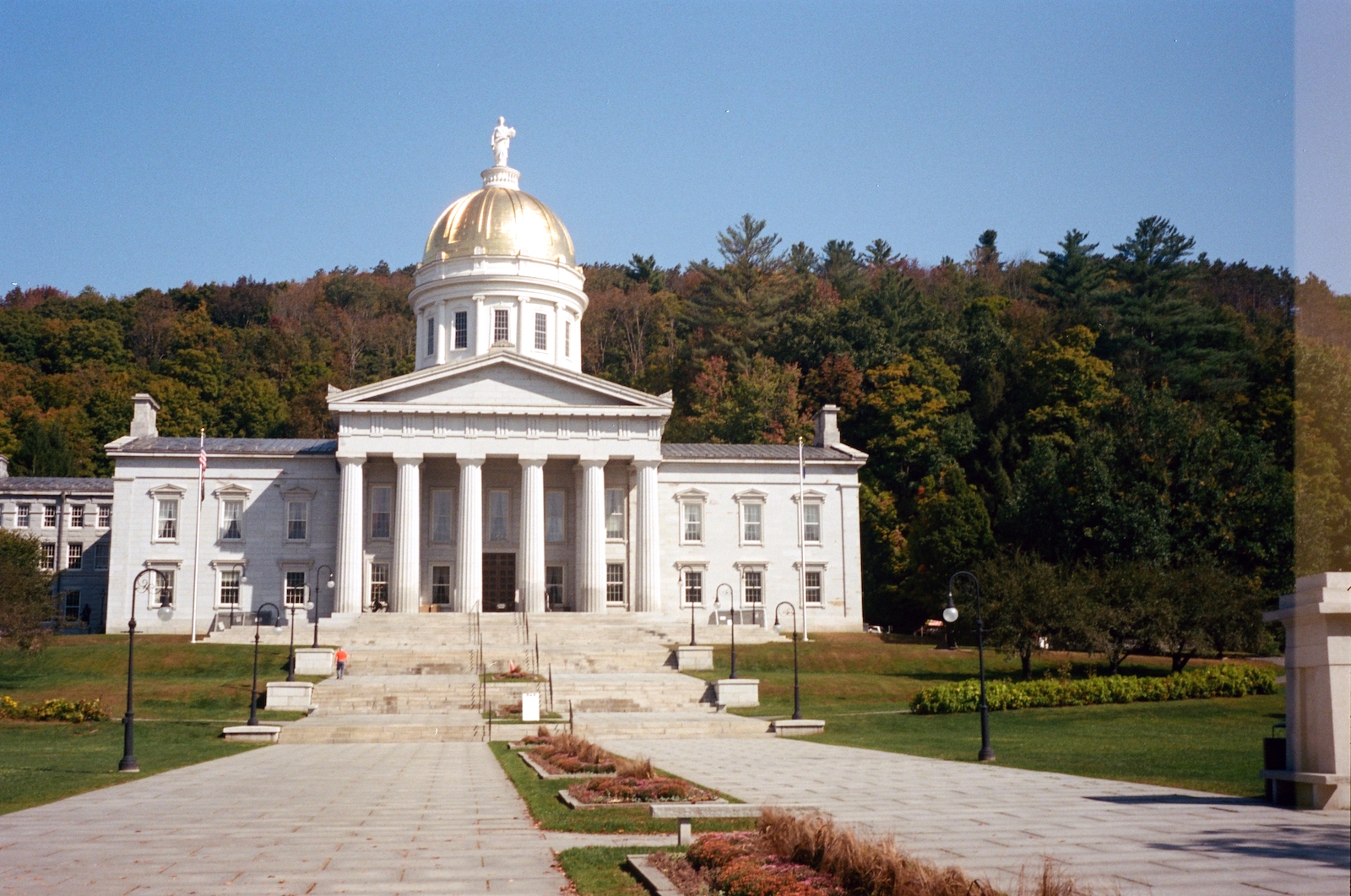 A government building with columns and a gold roof with statue on top